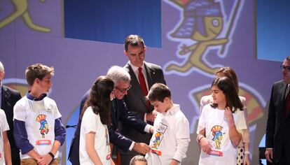 Felipe VI y el alcalde de Tarragona con niños que lucen la mascota de los juegos en la camiseta.