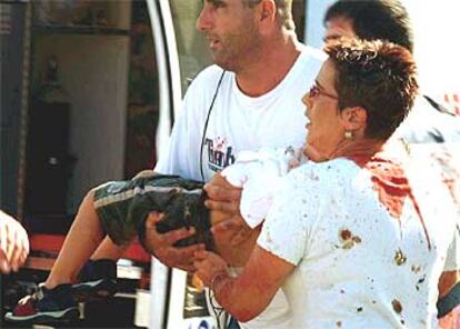 Dos transeúntes alejan a un niño herido del lugar del atentado en Haifa, al norte de Israel.