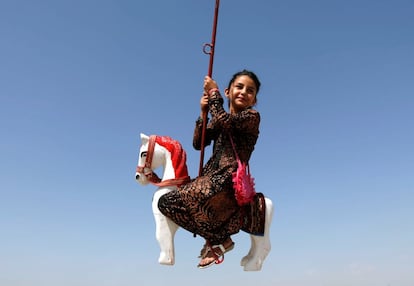 Una niña afgana monta en una atracción de feria durante el primer día de la fiesta musulmana de Eid al-Adha, en Kabul (Afganistán).