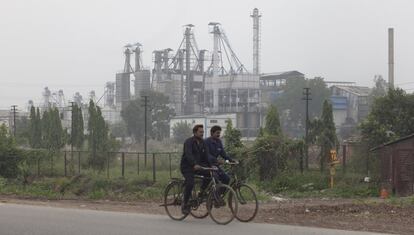 Dos hombres montan en sus bicicletas en frente de la planta de procesamiento de arroz Sunstar Overseas Ltd., en Nueva Delhi, India. Mientras que la ciudad sigue siendo una de las ciudades más contaminadas del mundo, muchas personas están tomando decisiones ecológicamente conscientes mediante el uso de medios de transporte no contaminantes.