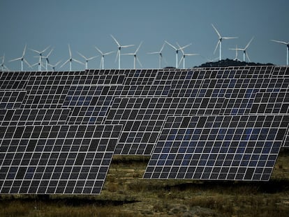 Varios paneles solares, con parques eólicos al fondo, en Navarra.