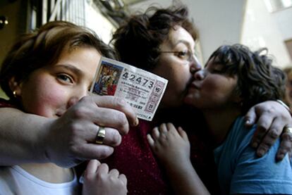 Una mujer y sus dos hijas se abrazan mientras muestran el décimo premiado con el &#39;gordo&#39; en la Cervercería Asturias de Valencia.