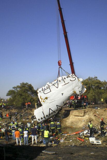 Una grúa iza parte del fuselaje del avión siniestrado.