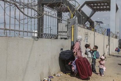 Una mujer y tres niños esperaban junto a la tapia de la frontera a que se abriera el paso de Rafah para pasar a Egipto, el lunes.