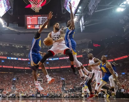 El jugador de Toronto Raptors Fred VanVleet rebotea ante la oposición de los jugadores de Golden State Warriors Kevin Durant y Kevon Looney.