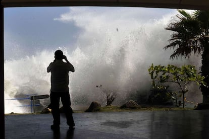 Un hombre toma una foto de las olas en La Libertad. Las autoridades destacan la importancia de tener en cuenta las recomendaciones de Protección Civil. Insisten en "mantenerse alejados de los muelles, puertos y playas, porque las corrientes de retorno aumentan la probabilidad de ahogados".