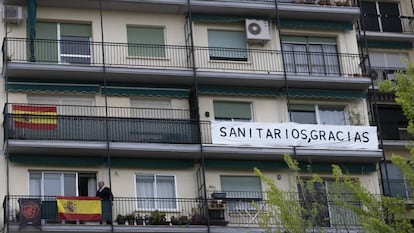 Un edificio con banderas de España y un cartel de apoyo a los sanitarios en Sevilla.