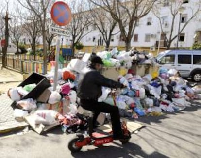 Un hombre pasa ayer ante la basura acumulada alrededor de varios contenedores en una calle de Sevilla.