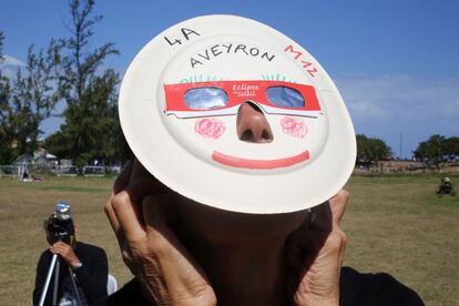 Una mujer observa el eclipse a través de unas gafas especiales, en la isla del Océano Índico de La Reunión.