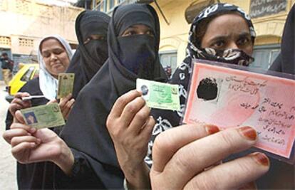 Unas mujeres paquistaníes hacen cola y enseñan sus documentos ante un colegio electoral de Rawalpindi.