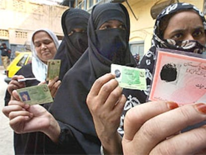 Unas mujeres paquistaníes hacen cola y enseñan sus documentos ante un colegio electoral de Rawalpindi.
