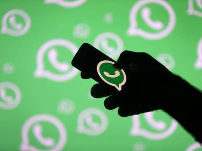 FILE PHOTO: A man poses with a smartphone in front of displayed Whatsapp logo in this illustration September 14, 2017. REUTERS/Dado Ruvic/File Photo