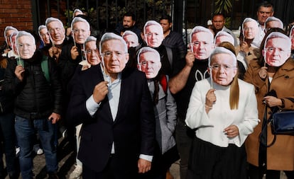 Varias personas usan mascaras con la imagen de Álvaro Uribe, en el complejo judicial de Paloquemao, en Bogotá.