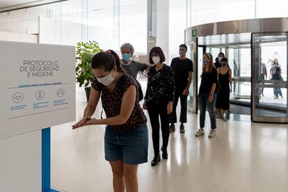 Los primeros visitantes de CaixaForum de Barcelona se lavan con gel las manos tras cruzar la puerta. 