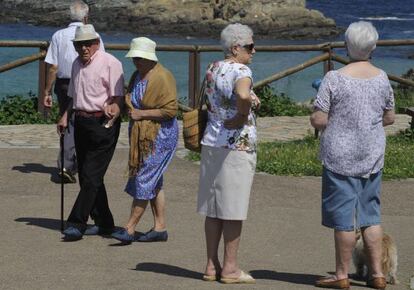 Personas mayores pasean cerca del mar en Tapia de Casariego (Asturias).