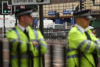 Dos agentes vigilan la estación de Stockwell, donde se ha producido el tiroteo en el que ha muerto el sospechoso.