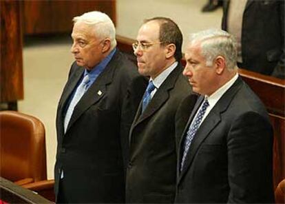El primer ministro israelí, Ariel Sharon, guarda un minuto de silencio en el Parlamento junto a dos ministros.