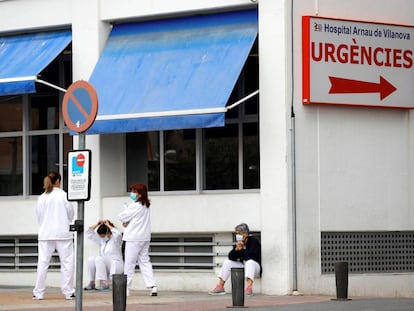 Personal sanitario del Hospital Arnau de Vilanova descansa unos minutos ante la puerta de urgencias.