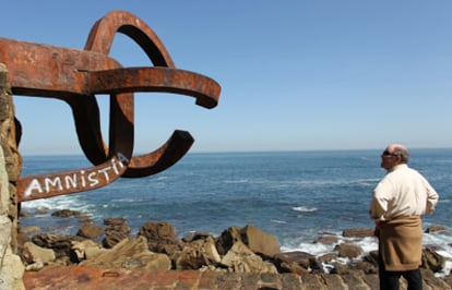 Una persona observa la pintada a favor de los presos de ETA en el <i>Peine de los Vientos</i>, obra del artista vasco Eduardo Chillida.