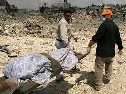 Dos palestinos cargaban ayer con el cadáver de uno de los muertos en el campo de Yenín.