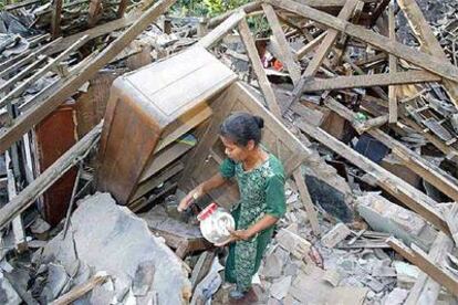 Una mujer trata de salvar algunas pertenencias de las ruinas de su casa.