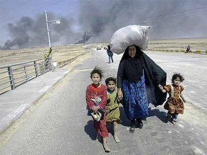 Una mujer iraquí huye de la guerra con sus hijos de la mano y sus pertenencias sobre la cabeza. La foto fue tomada al poco de iniciarse la invasión a las afueras de Basora.