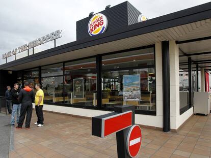 Tres jóvenes conversan en la entrada de un Burger King en Coslada.