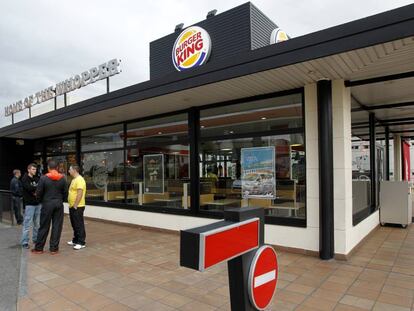 Tres j&oacute;venes conversan en la entrada de un Burger King en Coslada.