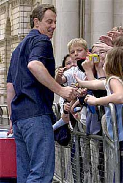 Tony Blair saluda a unos niños, al salir ayer de su residencia oficial.