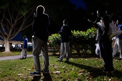 Migrantes somalíes que llegaron en patera a Mallorca intentan comunicarse con sus familiares desde el parque donde permanecen toda la noche, a la espera del ferri que los trasladará al día siguiente a la península, rumbo a distintos centros de acogida en España, el 7 de julio.
