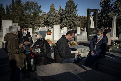 Varias personas leen algunos libros de Almudena Grandes, este lunes tras el funeral de la escritora en el Cementerio Civil de la Almudena.