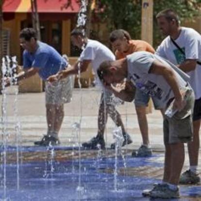 Unas personas se refrescan en una fuente céntrica de Sevilla.