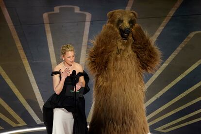 La actriz y directora Elizabeth Banks sube al escenario junto a una persona caracterizada del oso de la película 'Cocaine bear'. 
