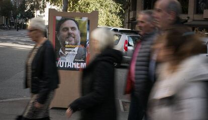 Ciudadanos caminan delante de un cartel de ERC con la imagen de Oriol Junqueras.