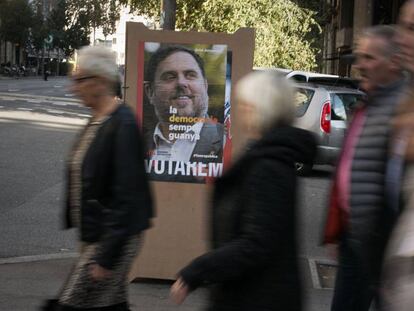 Ciutadans davant d'un cartell d'ERC amb la imatge d'Oriol Junqueras.