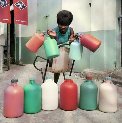 Una empleada de la tienda Sick Hagemeyer con las botellas utilizadas en el cuarto oscuro como guía para el revelado en color. Acra, 1970.