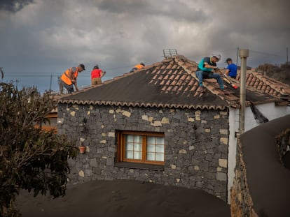 Varios voluntarios trabajan retirando cenizas de los tejados de casas próximas al volcán de Cumbre Vieja, el día 5 en La Palma.