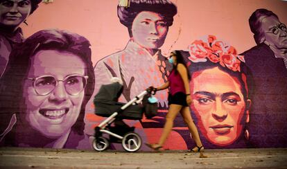 Una mujer camina junto al mural restaurado de las mujeres del barrio de Ciudad Lineal en Madrid, este sábado.