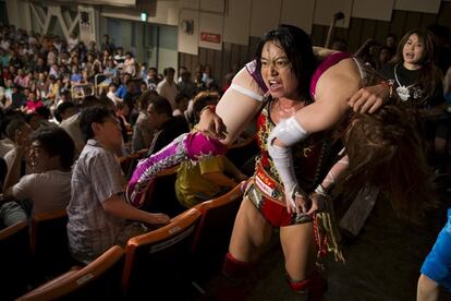 Wrestler Mieko Satomura carries her opponent  Kairi Hojo through the audience area during a Stardom female professional wrestling show at Korakuen Hall in Tokyo, Japan, July 26, 2015. Professional women's wrestling in Japan means body slams, sweat, and garish costumes. But Japanese rules on hierarchy also come into play, with a culture of deference to veteran fighters. The brutal reality of the ring is masked by a strong fantasy element that feeds its popularity with fans, most of them men. REUTERS/Thomas Peter    SEARCH "WOMEN WRESTLERS" FOR THIS STORY. SEARCH "THE WIDER IMAGE" FOR ALL STORIES