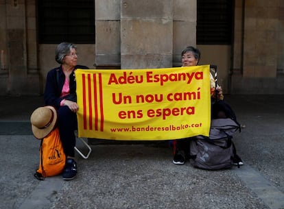 Dos mujeres sujetan un cartel con la leyenda "Adiós España, nos espera un nuevo camino" cerca del Parlament en Barcelona.