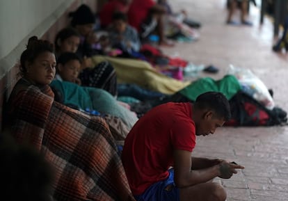 Venezuelan migrants sit along a building wall as they take cover from the rain, near the banks of the Rio Grande in Matamoros, Mexico, Saturday, May 13, 2023