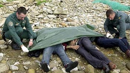 Dos guardias civiles cubren los cuerpos de tres inmigrantes ahogados en la costa de Tarifa.