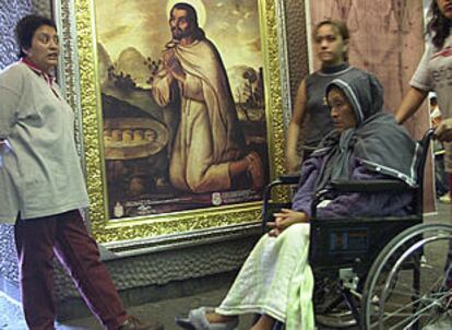 Una mujer en silla de ruedas pasa junto a un retrato del indio Juan Diego en la basílica de Guadalupe, en México.
