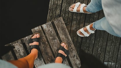 los pies de dos personas usando sandalias en un puerto