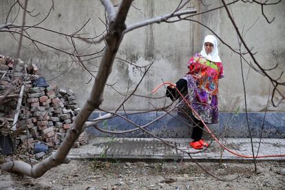 Zohreh Etezadossaltaneh, que nació sin brazos, riega su jardín con una manguera con el pie en Teherán, Irán.