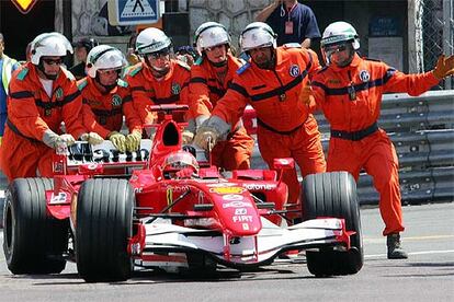 Los auxiliares de pista empujan el coche de Schumacher hacia el garaje.