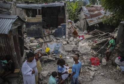 Una familia se alimenta frente a varias casas destrozadas por el terremoto, este domingo en Les Cayes.