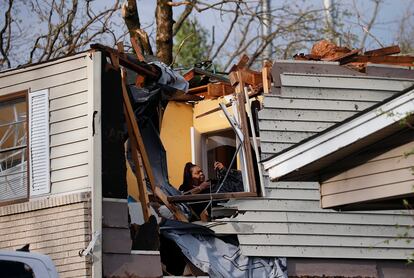 Una mujer reúne sus pertenencias luego de que el tornado de este viernes arrancara el techo de su vivienda.