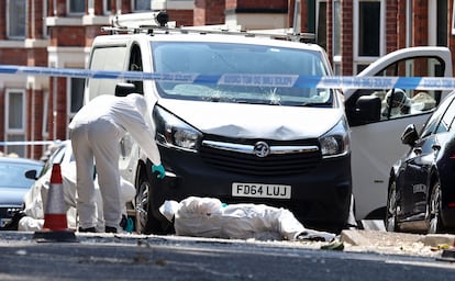 Police forensics officers work around a white van with a shattered windscreen, inside a police cordon on Bentinck Road in Nottingham, central England.