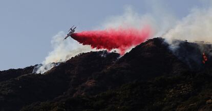 Un avión contraincendios esparce agua sobre una colina cerca de un incendio forestal en Azusa, California.